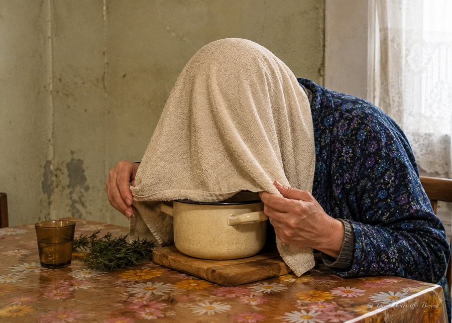 man standing over a steaming pot of water with a towel thrown over your head and inhaling vapors to help him relieve a stuffy nose