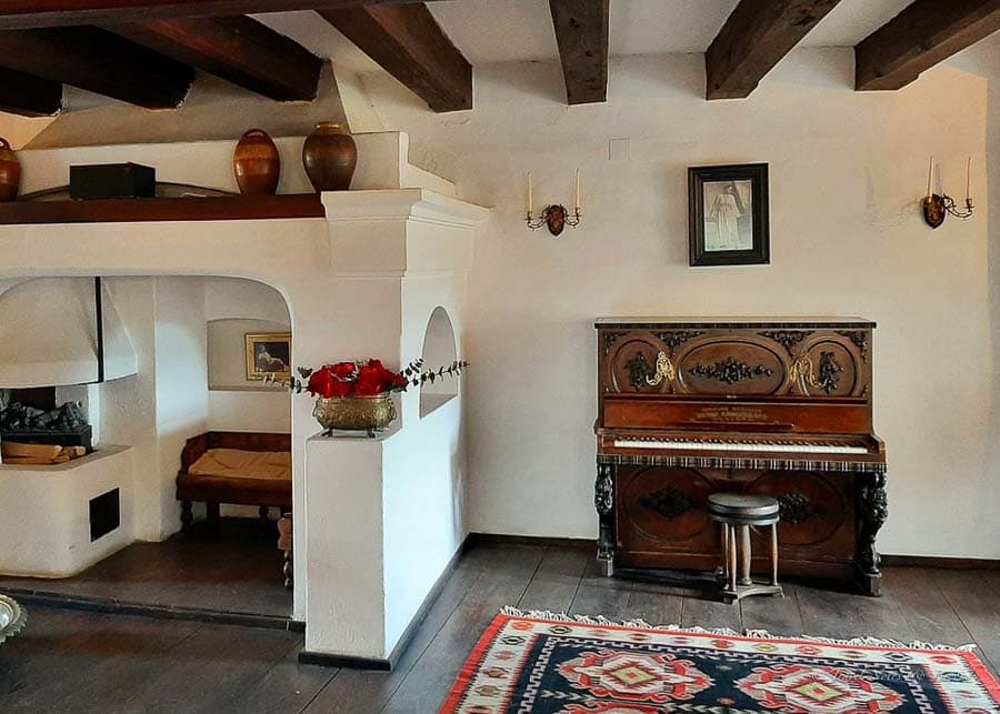 Furnished room displaying an old piano and a peasant stove