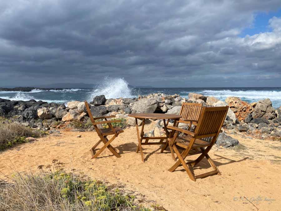 imge depicting chairs and a table on the beach